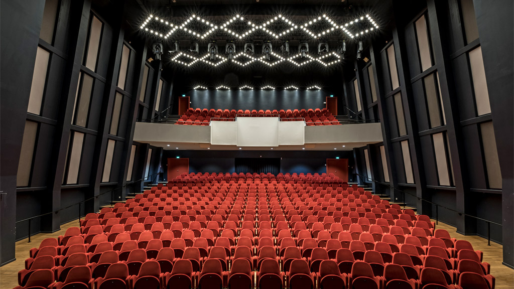 Teatersalen i Musikhuset Esbjerg. Røde sæder, mørke vægge og lysriggen tændt.